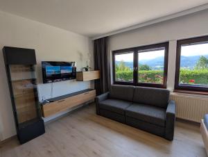 a living room with a couch and a tv and windows at Herzogberghof in Kindberg