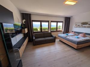 a bedroom with a bed and a couch and a television at Herzogberghof in Kindberg