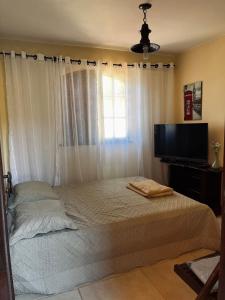 a bedroom with a bed and a flat screen tv at Encanto da Serra 2 in Miguel Pereira