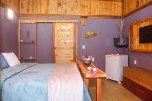 a bedroom with a bed and a table and a television at Espaço Gata Mourisca in Camanducaia