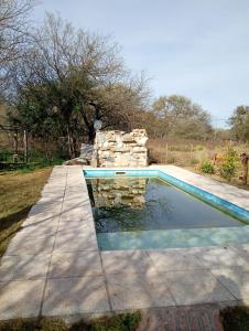 a swimming pool with a stone wall next to it at Lo de iaia in Carpintería