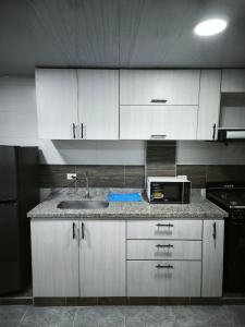 a kitchen with white cabinets and a sink and a microwave at Apartaestudio en Cali in Cali