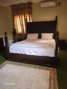 a bedroom with a bed with white sheets and a window at Afiraiserviceapartment in Kaduna