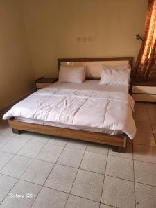 a bed with white sheets and pillows in a bedroom at Afiraiserviceapartment in Kaduna