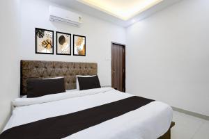 a bedroom with a large white bed and some pictures on the wall at Hotel O White House in Rānchī +27 photos
