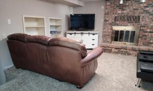 a brown leather couch in a living room with a television at Dakota Lodge in Dickinson