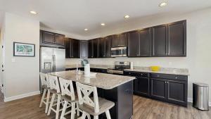 a kitchen with black cabinets and a kitchen island with bar stools at Bethany Woods - 31600 Charleys Run in Bethany Beach