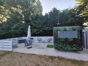 a patio with an umbrella and chairs and a fence at Carabois in Esson