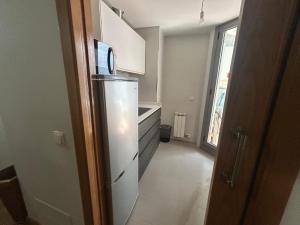 a small kitchen with a refrigerator and a window at Petit con piscina in Pontevedra