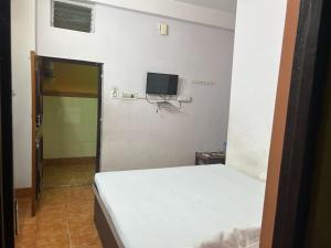 a small bedroom with a bed and a television at Priyadarshi Hotel in New Digha