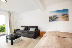 a white bedroom with a bed and a couch at Fördeperle Laboe in Laboe