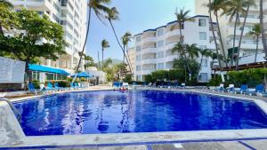 ein großes Schwimmbecken mit blauen Stühlen und Gebäuden in der Unterkunft Hotel Acapulco Malibu in Acapulco