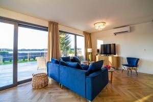 a living room with a blue couch and a large window at Velur Haus in Borne Sulinowo