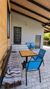 a patio with two blue chairs and a wooden table at Хата над гуком in Kosiv