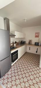 a kitchen with white cabinets and a tile floor at La mie du Hom in Thury-Harcourt +6 photos