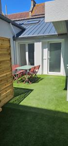 a patio with a table and chairs on the grass at La mie du Hom in Thury-Harcourt