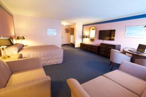a hotel room with a bed and a couch and a desk at Hôtel Motel Le Voyageur in Saint-Georges