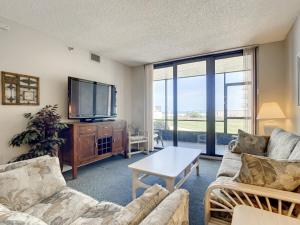 a living room with a couch and a tv at Beachfront with a pool at Ocean Trillium Condo ~ 101 in New Smyrna Beach