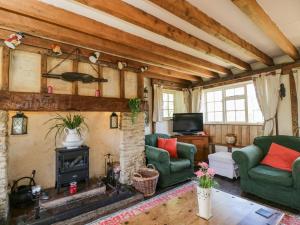 a living room with a fireplace and green chairs at Ivy Cottage in Bath