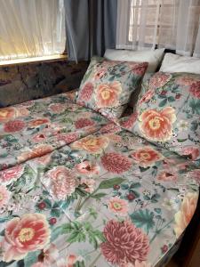 a bed with a floral comforter and pillows on it at Lille Ro in Giskemo