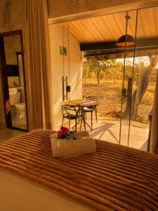 a bedroom with a bed with a table and a view at Flats Araras do Vale in Colinas Do Sul