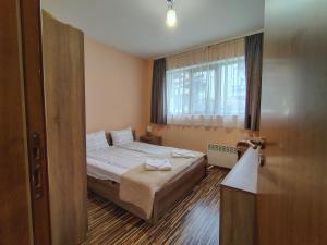 a small bedroom with a bed and a window at Апартамент за гости Александър in Chepelare