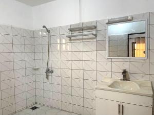 a white tiled bathroom with a sink and a mirror at RESIDENCE Chez PETER in Alakopé +17 photos