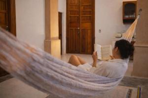 a woman laying in a hammock reading a book at Casa Näab Centro de Merida in Mérida