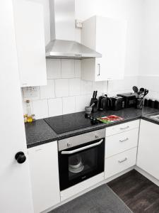 a kitchen with white cabinets and a stove top oven at Roclems Homes in Grays Thurrock