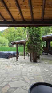 a patio with a wooden roof and a tree at Къща за гости ХидроТера - Велинград in Velingrad
