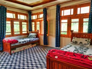 a bedroom with two beds and windows in it at Mirza Luxe Inn Astore in Astor