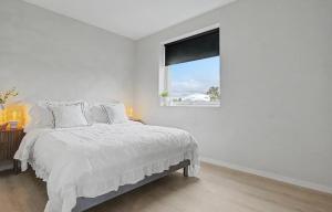a white bedroom with a bed and a window at Central apartment in quiet area in Ålesund