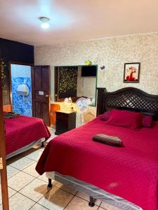 a bedroom with two beds with red comforter at Cristales de Antigua Hotel Cristal in Antigua Guatemala