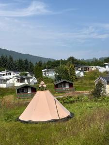 a tent in the middle of a field with houses at Lille Ro in Giskemo