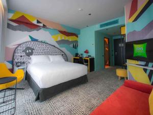 a bedroom with a bed and a colorful wall at ibis Styles Tbilisi Center in Tbilisi City