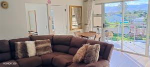 a brown couch in a living room with a large window at Elim Rest Place in Fisherhaven