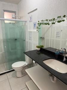 a bathroom with a sink and a toilet and a glass shower at Primos Hostel & House in Búzios +68 photos
