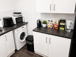 a kitchen with a washing machine and a microwave at Roclems Homes in Grays Thurrock