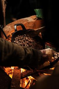 a person cooking food in a pan over a fire at Tupa Lodge Selva y Rio in Puerto Iguazú +33 photos