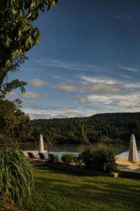 a view of a lake with two lawn chairs and umbrellas at Tupa Lodge Selva y Rio in Puerto Iguazú