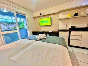 a bedroom with a bed and a kitchen with a tv at Executive - 106 No Garage in Caxias do Sul