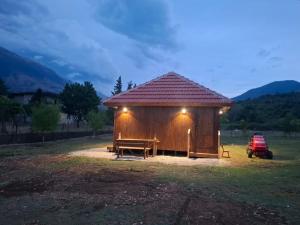 a small hut with a bench in a field at Vjosa Valley Glamping in Tepelenë
