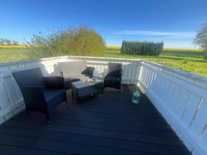 a deck with chairs and tables on a white railing at Hochsitz Appartement in Seelitz