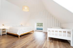 a white bedroom with two beds and a window at Huus 41 in Wulfen auf Fehmarn
