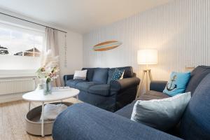 a living room with two blue couches and a table at Huus 41 in Wulfen auf Fehmarn +29 photos