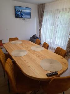 a wooden table with chairs and a remote control on it at Casa de vacanta Gea Transalpina in Şugag