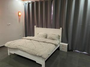 a bedroom with a white bed with a gray curtain at Khartoum Nights in Kigali