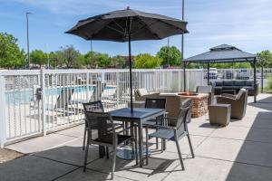 a table and chairs with an umbrella next to a pool at Residence Inn by Marriott Albuquerque North in Albuquerque