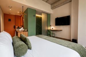 a bedroom with a white bed and a television at Hunters Hotel Medellin in Medellín