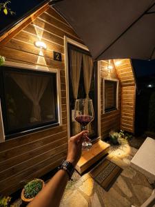 a person holding a glass of wine in a cabin at Koman Twin Cabins in Gushtë +18 photos